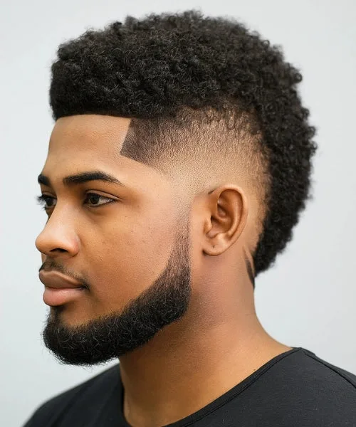 Frohawk fade with coiled crown and clean tapered sides for defined curly structure.