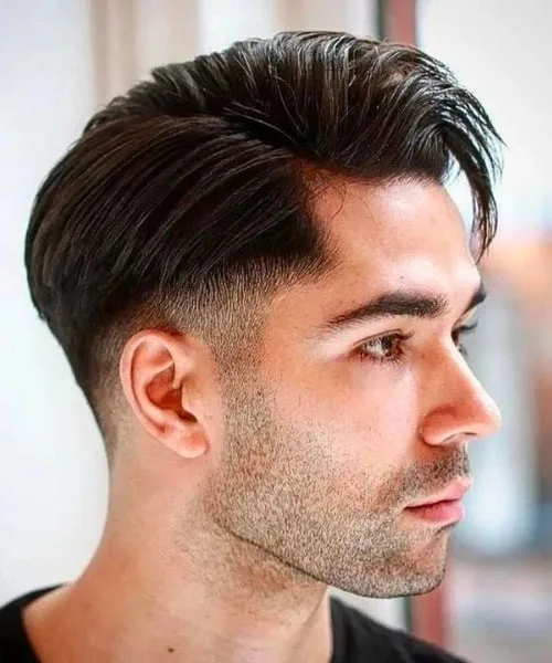 Low fade side part hairstyle with clean tapered sides and sleek, voluminous parted top.