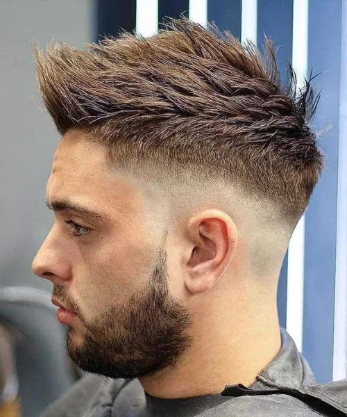 Medium fade Faux Hawk with textured volume and choppy top for a trendy, youthful look.