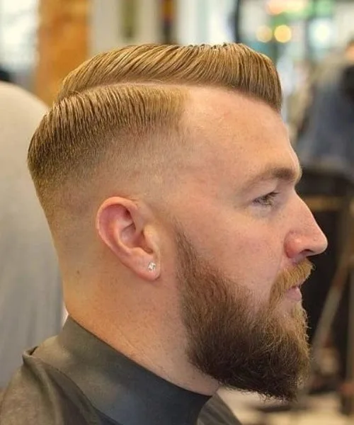Comb over haircut paired with full beard for masculine style featuring sleek top and faded sides