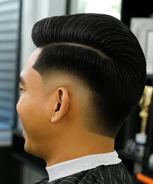 Comb over burst fade haircut with rounded fade around ear and brushed top for trendsetting appeal