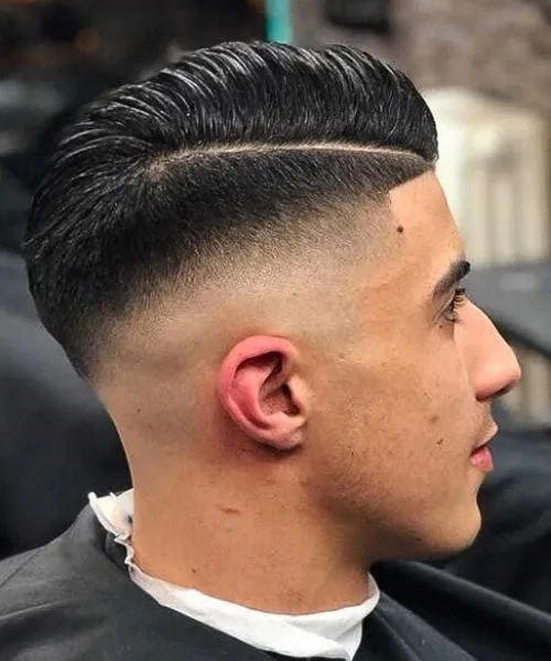 Comb over drop fade haircut with smooth side part and fade curving neatly behind the ear