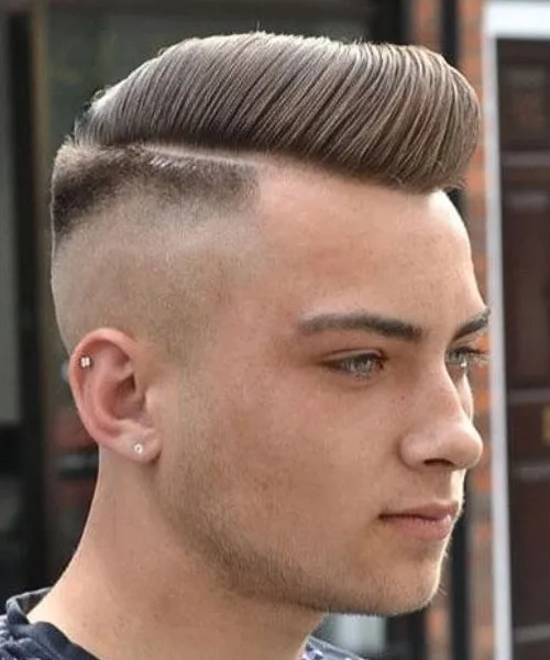 High fade comb over haircut with sharp sides and voluminous top for a bold, trendsetting style