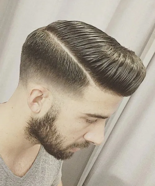 Comb over pompadour haircut with voluminous brushed top and sharp fade for bold stylish finish