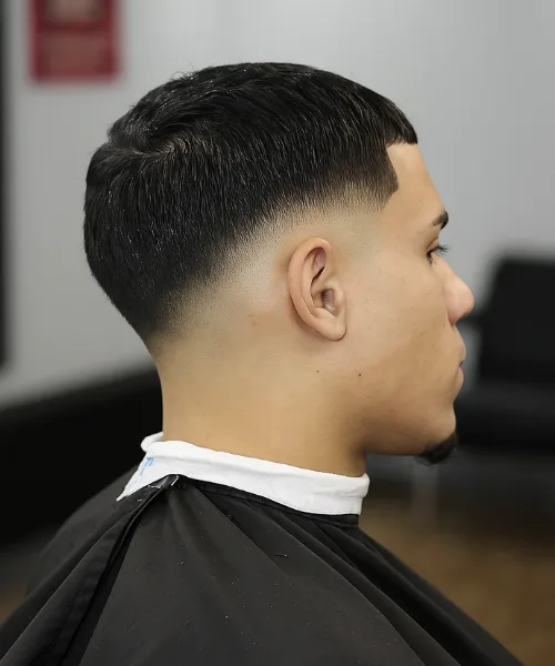 Drop skin fade haircut with faded contour behind the ear and styled voluminous top