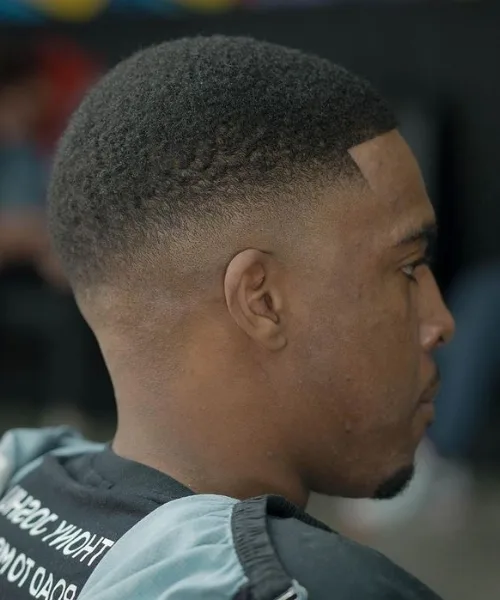 Skin fade haircut for Black men with defined curls on top and sharp skin-faded sides