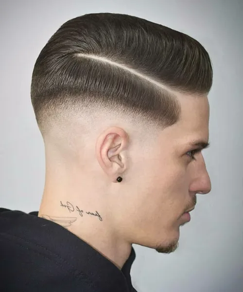 Skin fade comb over haircut with clean parting and slicked side styling for sharp polish