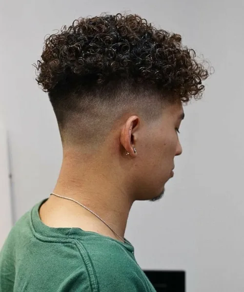 Skin fade curly haircut with natural curls on top and clean faded sides for contrast