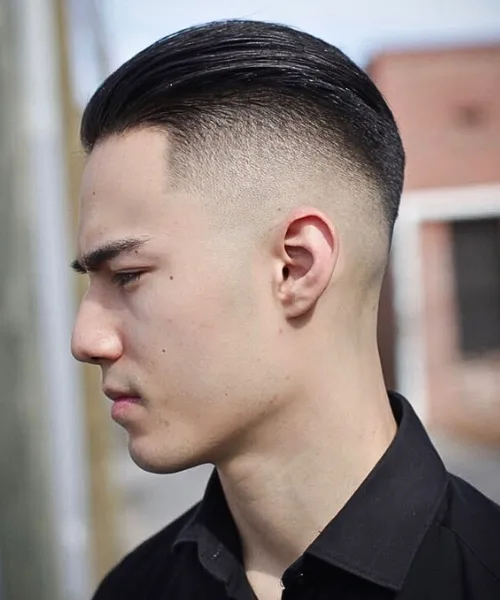 Skin fade slick back haircut with sleek brushed top and faded sides for polished style