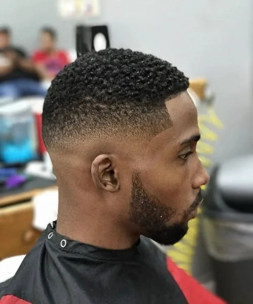 Black men’s Caesar cut with short cropped curls, clean fade, and defined curl texture on top