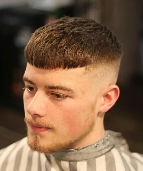 Caesar cut with blunt fringe, faded sides, and forward-layered textured top for volume