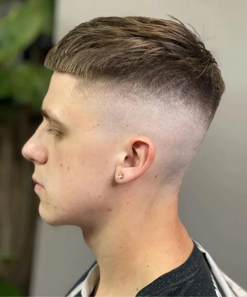 High fade side part haircut with clean part line and voluminous top for structured finish