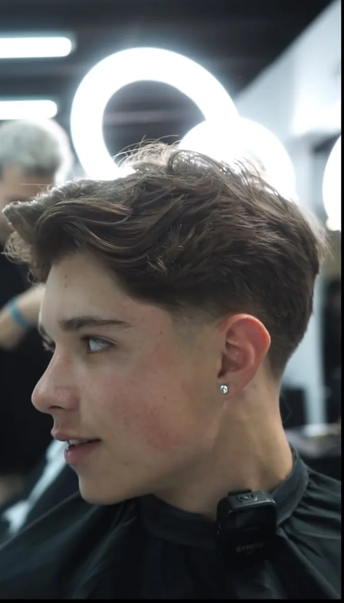 Brushed up low taper fade on straight hair with the top pushed up and back